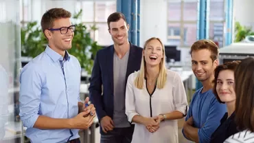 Group of people smiling and chatting in an office setting