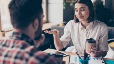 Two people having a discussion over coffee at a table.