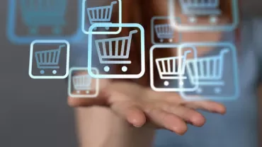 Open hand supporting floating digital shopping cart icons.
