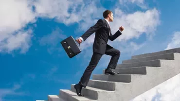 Person in business attire climbing stairs towards the sky.