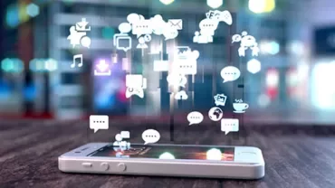 Smartphone on table with floating social media and app icons.