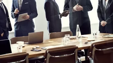 Business meeting with professionals in suits around a conference table.