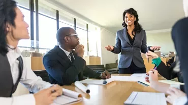Person leading a meeting with colleagues at a conference table.