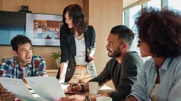 Group of people having a discussion around a table with documents.