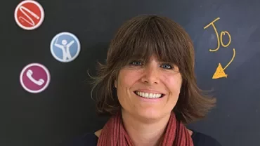 Person smiling in front of a blackboard with colorful icons.