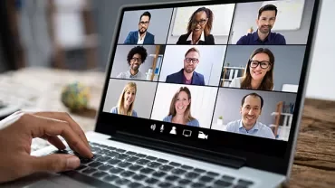 Laptop screen showing a group video call with nine participants.