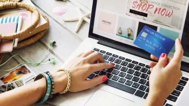Person using laptop for online shopping with a credit card.