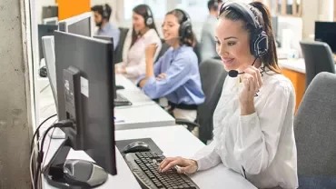 People in an office using computers and headsets.