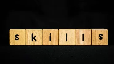 Wooden blocks spelling 'skills' on a black background.