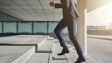 Person in business attire running up outdoor steps.
