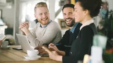 Group of people smiling and working together at a table.