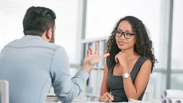 Two people having a discussion at a desk with documents.
