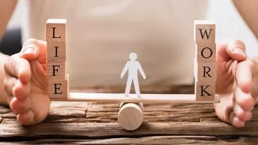 Wooden blocks with 'Life' and 'Work' balanced on a seesaw