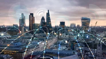 City skyline with modern skyscrapers and digital network overlay.