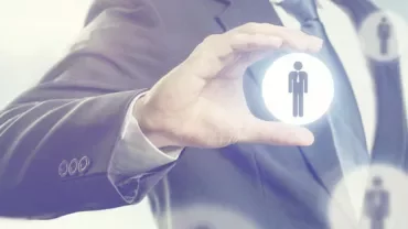 Person in a business suit holding a glowing icon of a figure.