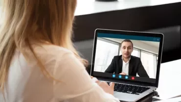 Person having a video call on a laptop at a desk.