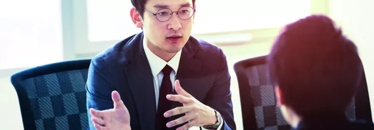 Person in a suit discussing with another individual at a meeting.