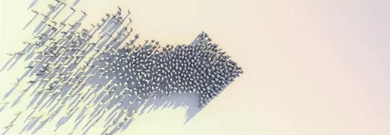 A group of people forming the shape of an arrow on a flat surface.