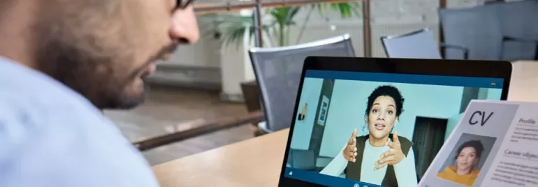 Person attending a virtual meeting on a laptop showing another individual talking on the screen.