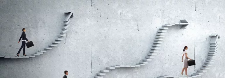 People walking on different staircases against a concrete wall.