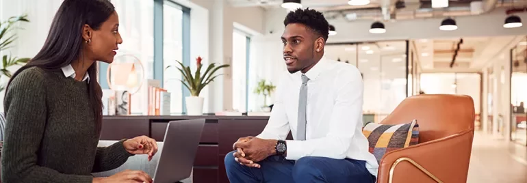 Two people seated in a modern office, engaged in conversation.