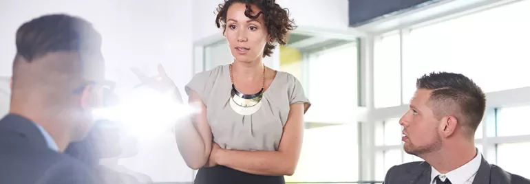 Person speaking to colleagues in a bright office.