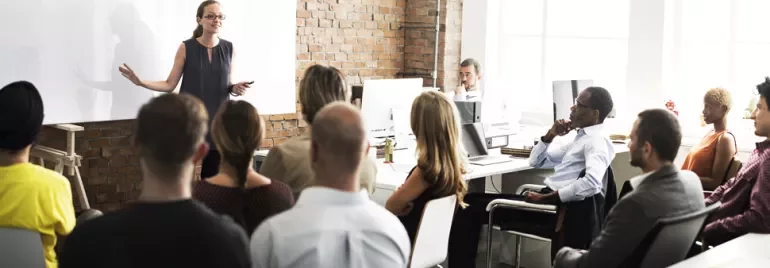 Person giving a presentation to a group in a modern office setting.