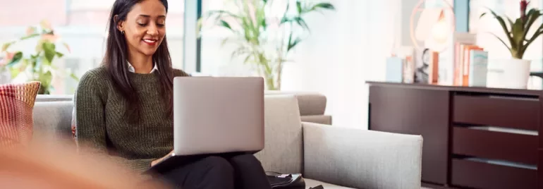 Person sitting on a couch working on a laptop in a modern office setting.