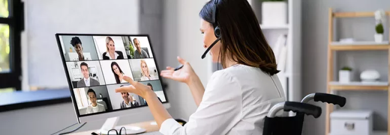 Person on video call, wearing headset, gesturing towards screen with multiple participants displayed.