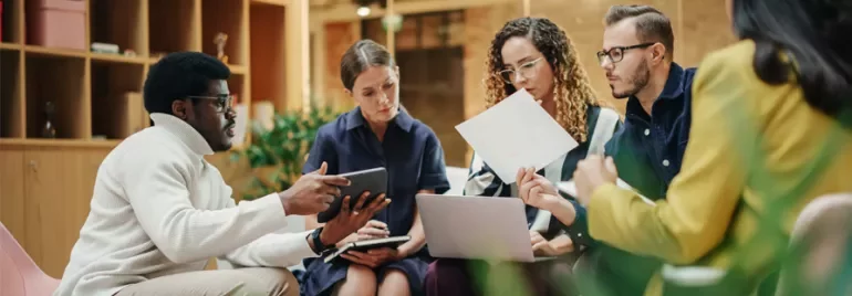 Group of people having a meeting with laptops and papers.