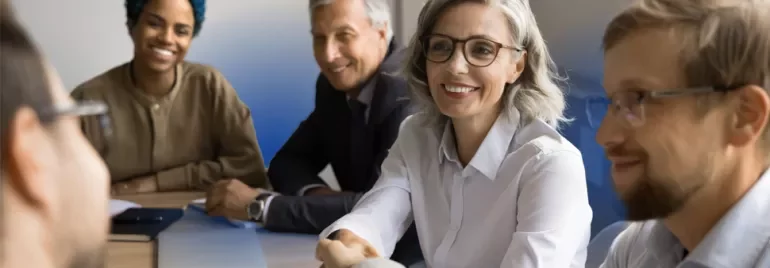 5 people in a meeting room smiling