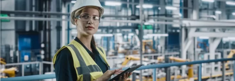 woman in hard hat holding clipboard in factory