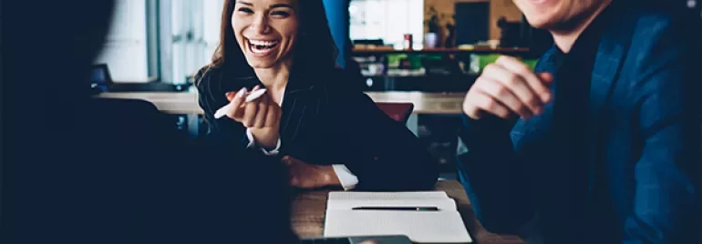 Group of people smiling and having a discussion in a modern office setting.