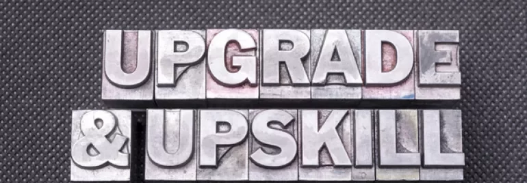 Metal letters spell 'Upgrade & Upskill' on a textured background.