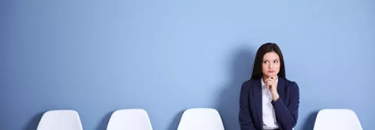 Person sitting on a chair in a room with a blue wall and a clock.