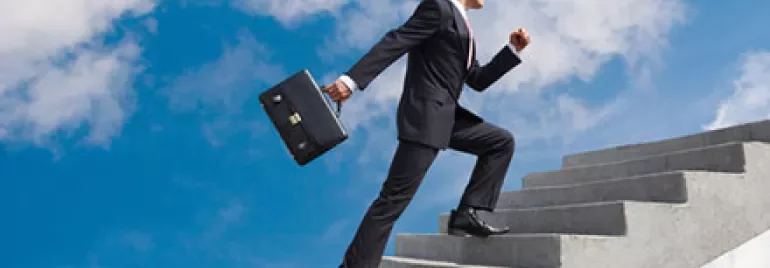 Person in business attire climbing stairs towards the sky.