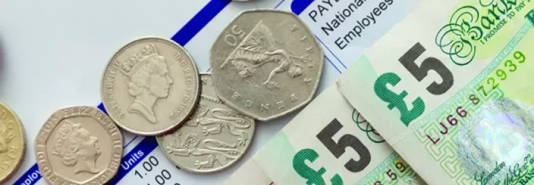 British coins and banknotes on a payslip.