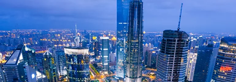 A vibrant cityscape at dusk with illuminated skyscrapers and a bustling skyline.