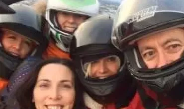 Group of people wearing helmets taking a selfie outdoors.