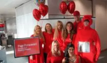 Group in red attire posing with festive balloons.