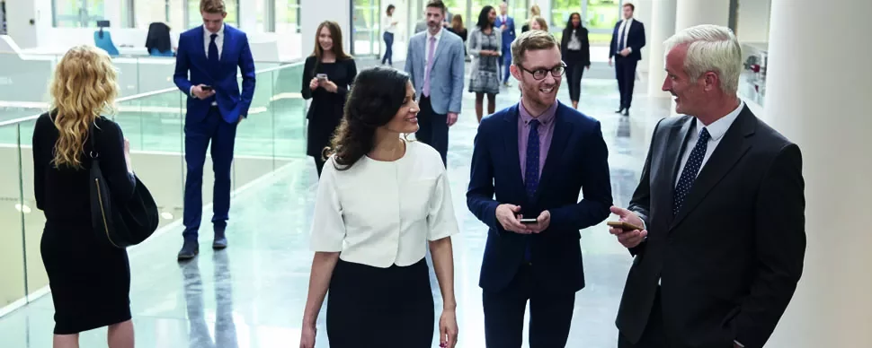 Group of people walking in a modern office hallway.
