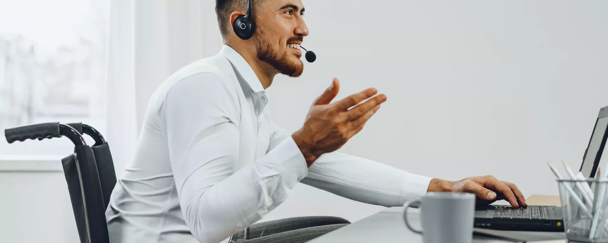 Person in white shirt smiling, using a laptop with headphones.