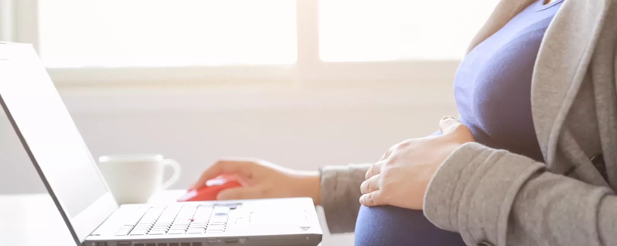 Person with hand on belly working on a laptop