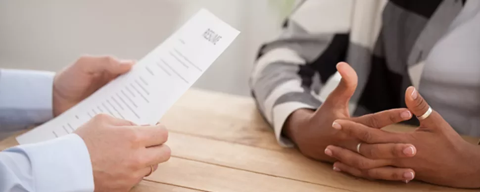 Person reviews a resume at a table during an interview.