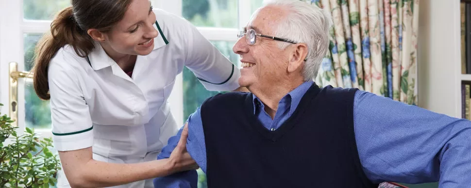A healthcare professional assisting an older adult in a bright room.