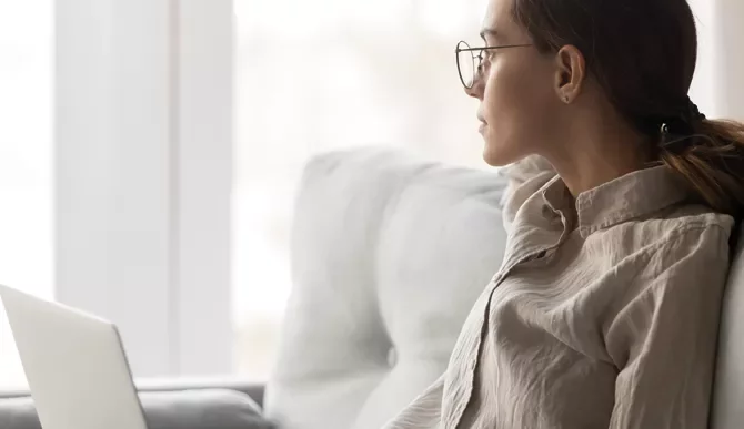 Person sitting on a couch, looking out a window.