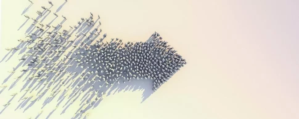 A group of people forming the shape of an arrow on a flat surface.