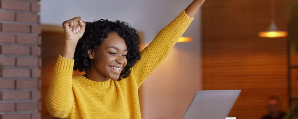 Person celebrating success while using a laptop.