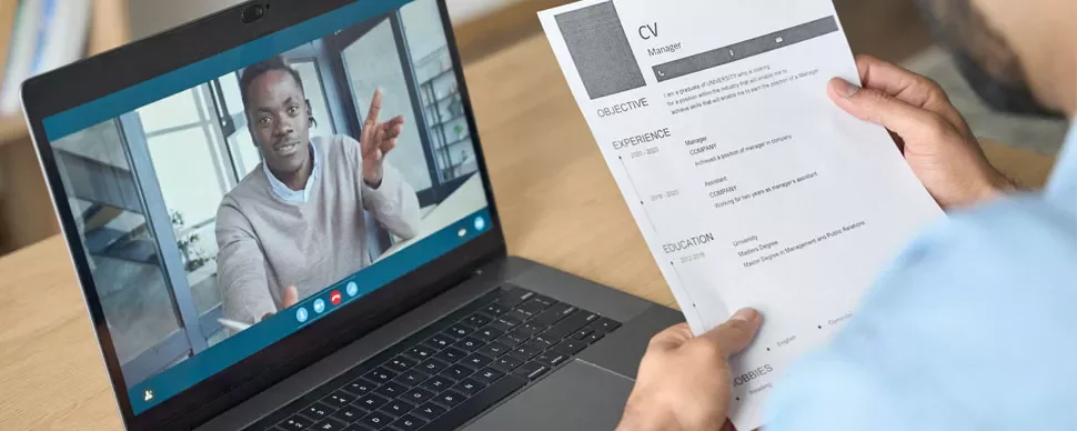Person on video call, holding a resume in hand.