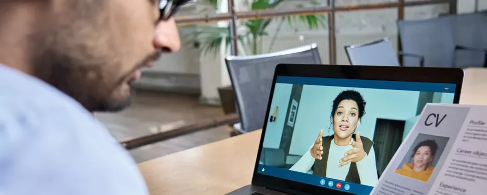 Person attending a virtual meeting on a laptop showing another individual talking on the screen.